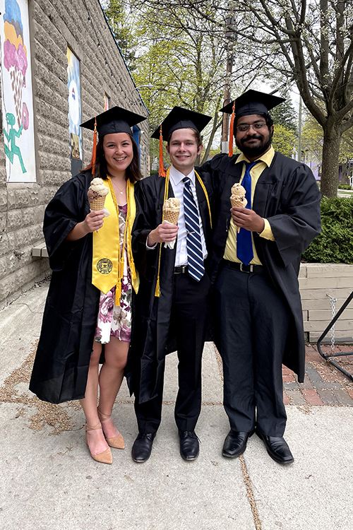 3 students in grad cap and gowns with ice cream cones